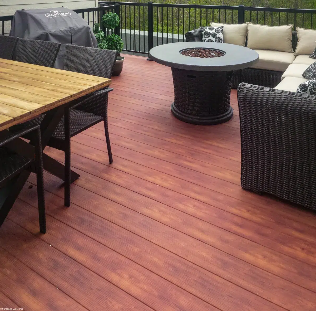 Une terrasse en aluminium avec des sièges en osier et un foyer confortable, parfait pour les rassemblements en plein air et la détente en soirée.