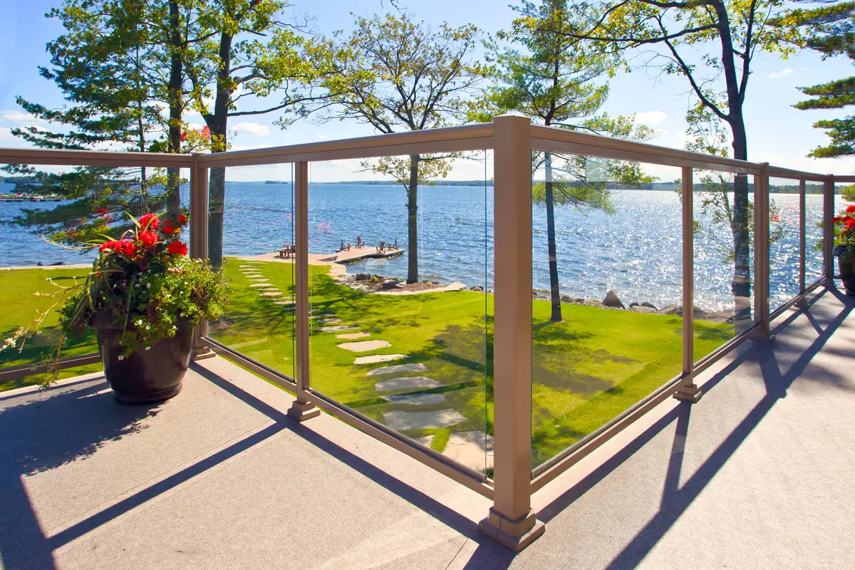 Garde-corps en aluminium beige avec panneaux de verre donnant sur une vue panoramique sur le lac