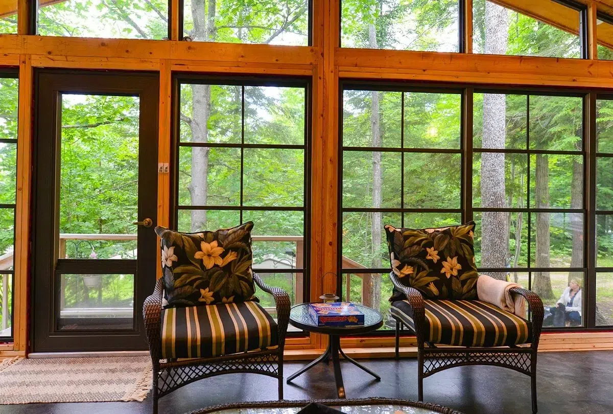 Une véranda magnifiquement conçue avec WeatherMaster, offrant une vue imprenable sur une verdure luxuriante avec une ambiance chaleureuse et rustique.